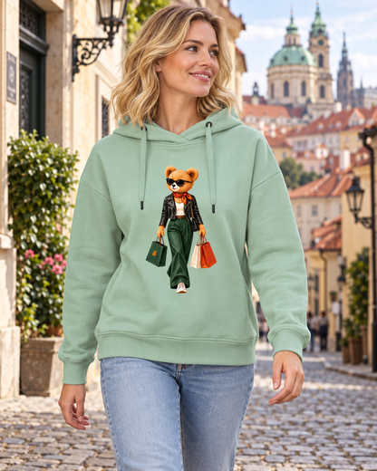 Žena v šalvějové mikině Shopping Is My Cardio s potiskem medvídka při procházce ulicí na Malé Straně.