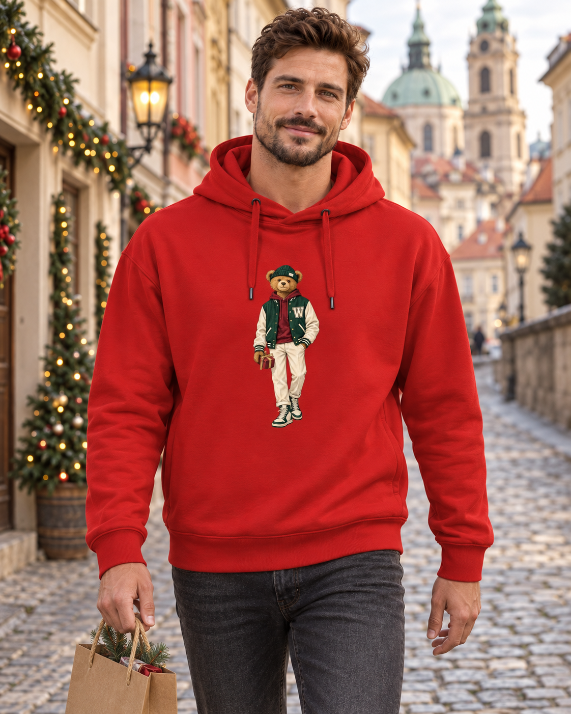 Man in a red Winter Club bear hoodie carrying a gift bag on a Prague street.